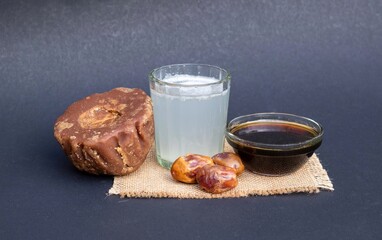 Date Palm Juice or Khejur Ras and Liquid and Hard Date Palm Jaggery and Fruit Isolated on Black Background with Copy Space, Also Known as Date Palm Sap or Khejur Rosh