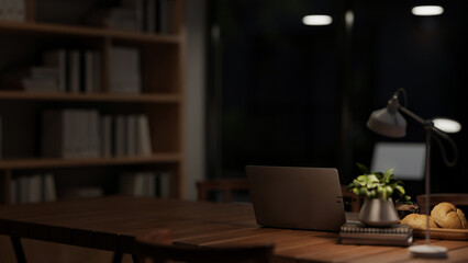 A laptop computer on a meeting table under a dim light from a table lamp in a meeting room at night.