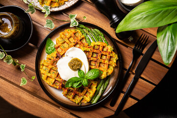 Savory zucchini Waffles with burrata cheese, pesto and asparagus. Garden table.