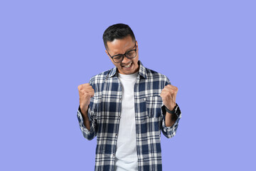 Fototapeta premium portrait of a young handsome Asian man making a success gestures isolated in a purple background