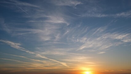 A beautiful sunrise with the sun just above the horizon, casting a warm golden glow. Wispy clouds...