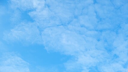 A clear blue sky with a pattern of fluffy, white clouds. The clouds are densely packed, creating a...