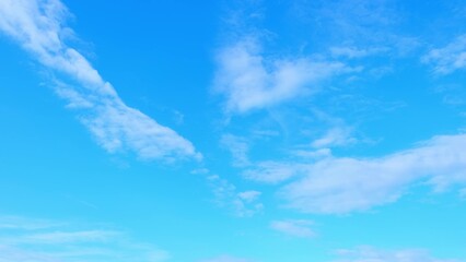 A bright blue sky with a few scattered, wispy clouds. The clouds are white and thin, creating a...