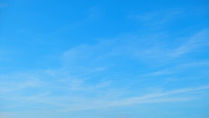A clear blue sky with faint, wispy clouds dispersed throughout. The sky's gradient transitions from a deeper blue at the top to a lighter blue near the horizon, creating a calm and tranquil scene.
