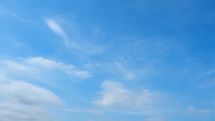 A serene blue sky with a few scattered white clouds. The clouds are thin and wispy, giving the sky...