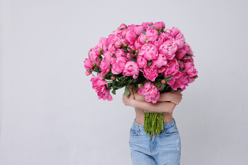 huge bouquet of peonies, Woman holding huge bunch of pink peony flowers covering her body and face on a white background