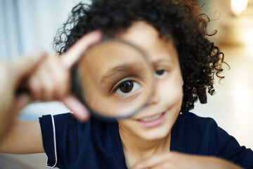 Boy, portrait and magnifying glass for eye in home, explore and kid play for investigation. Male...