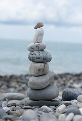 Balanced pebble pyramid silhouette on the beach with the ocean in the background