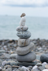 Balanced pebble pyramid silhouette on the beach with the ocean in the background