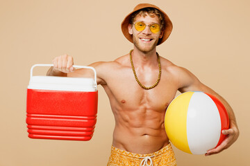 Young sexy man wearing yellow shorts swimsuit hat relax rest near hotel pool hold inflatable ball,...