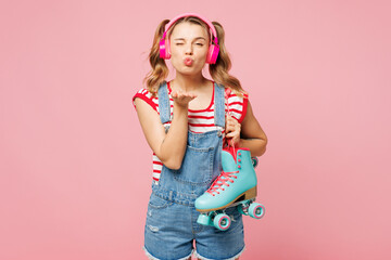 Young woman wear red t-shirt denim overalls casual clothes hold blue rollers listen music in...