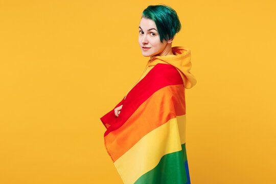 Side profile view young happy lesbian woman with dyed green hair wear hoody casual clothes looking camera isolated on plain yellow orange background studio portrait. LGBT diversity lifestyle concept.