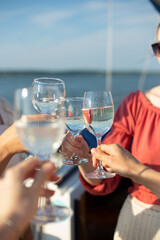 A close-up shot of friends clinking sparkling wine glasses at sunset on a yacht. Vacation, travel,...