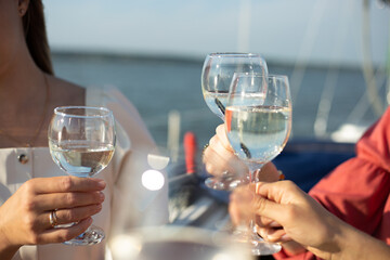 A close-up shot of friends clinking sparkling wine glasses at sunset on a yacht. Vacation, travel,...