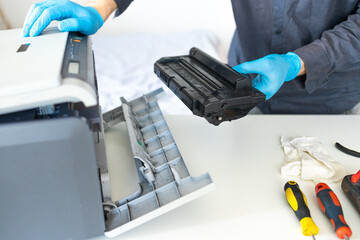 Repairman with screwdriver fixing modern printer in office.