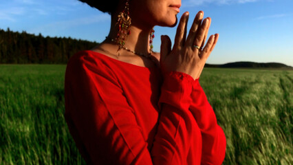 Young pretty girl woman meditating with closed eyes. Stock clip. Praying while standing in a field...