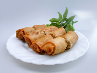 Golden brown deep fried spring roll, cut showing the filling insert, served in a white plate, easy to find in Thailand, local food, business concept