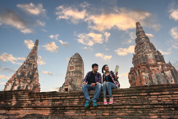 Tourists with map in hand looking at a temple in Ayutthaya, Thailand at Wat Mahathat