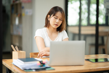 Asian business woman working on computer looking at documents at office