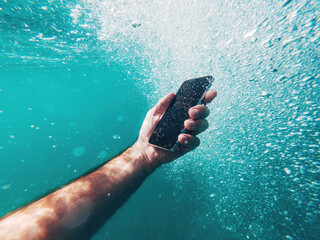 Man using smartphone device underwater in deep blue sea during summer holiday vacation