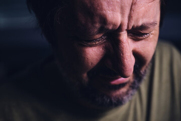 Man crying in dark room, sadness and grief concept, low key