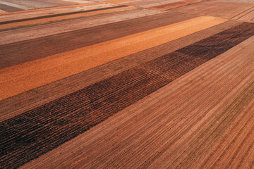 Aerial shot of harvested agricultural crop field forming beautiful colorful pattern from drone pov