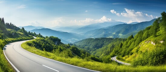 Scenic country road winding through lush green mountains in summer with copy space image