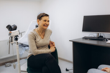Senior woman sitting on the gynecological chair during a medical consultation with gynecologist....