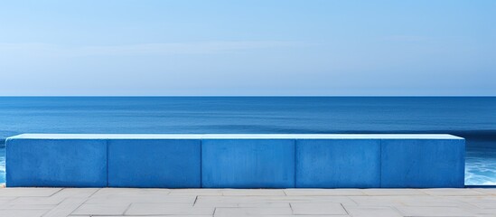 Blue and white concrete structure provides a breakwater for waves and protects the shore with a blank copy space image in the background
