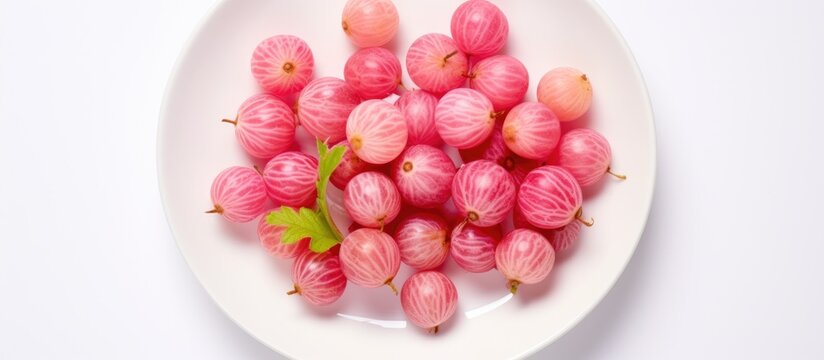 Top view of pink gooseberries on a white plate creating a vibrant copy space image for summer food with a berry harvest theme
