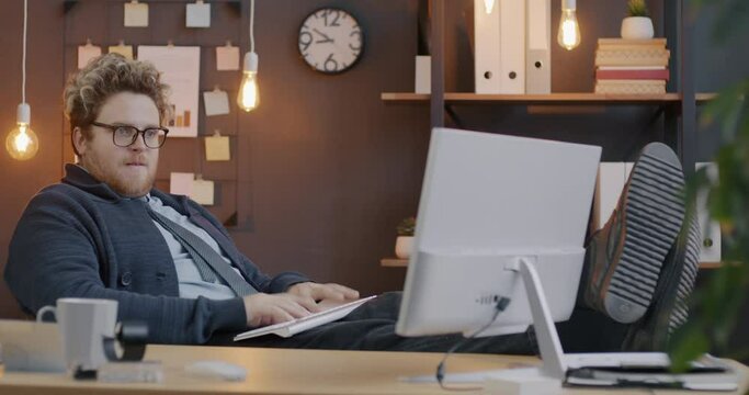 Loop of stressed employee typing and looking at computer screen working hard in illuminated office in evening. Modern technology and business concept.