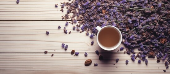 Top view of a white porcelain cup filled with dried lavender flowers scattered on a wooden surface with copy space image