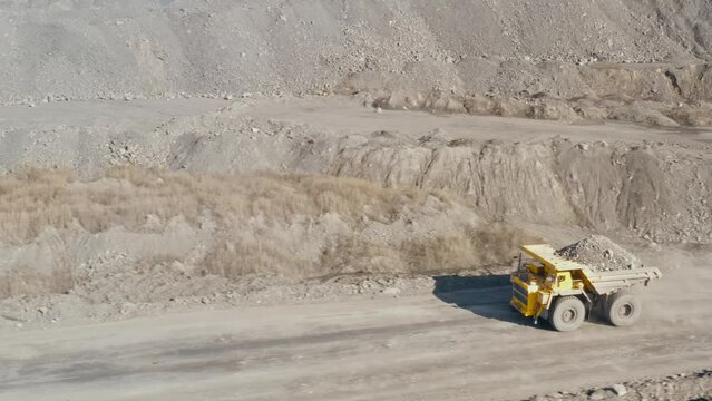 Large quarry dump truck. Loading rock in dumper. Loading coal into truck. Mining car machinery to transport coal. Open pit mine quarrying extractive industry stripping work. Big Yellow Mining Trucks