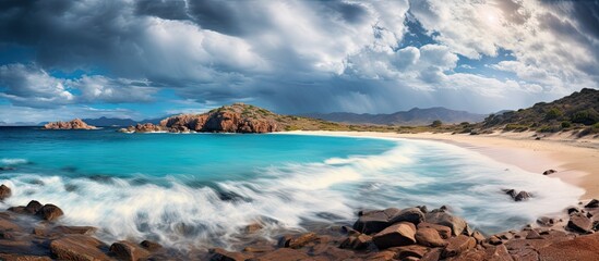 A serene beach with turquoise lagoons a rugged rocky shore and a dramatic storm approaching in the distance providing a perfect copy space image - Powered by Adobe