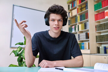 Web cam portrait of college student guy in headphones looking talking to camera