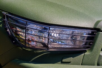 The headlight is protected. A metal grille is attached to the headlight.