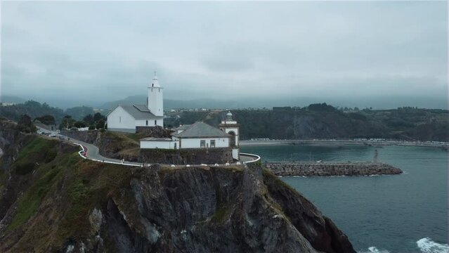 Lighthouse on top of a cliff on an overcast day. Cantabrico ocean cliff. Luarca, Spain.
