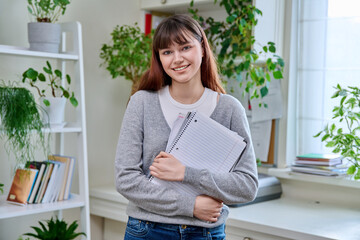 Portrait of smiling female student, 19,20 years old, looking at camera, in home interior