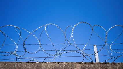 Barbed wire on a concrete fence. Panoramic photo.