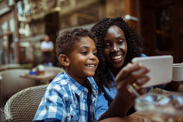 Black mother and son taking a selfie at a cafe