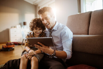 Happy young father and son with tablet at home