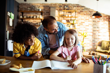 Father helping children with homework in kitchen