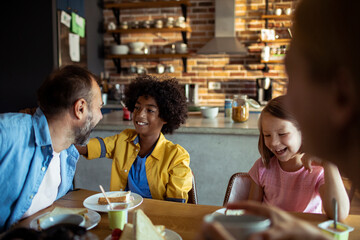 Multiracial family laughing together at breakfast table