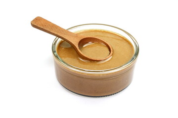 Sesame sauce in a bowl with wooden spoon isolated. Tahini isolated on white background