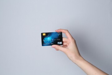Woman holding credit card on light grey background, closeup
