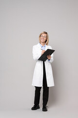 Smiling doctor with clipboard on grey background