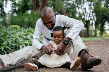 Fototapeta premium African father and baby girl playing sitting on a park