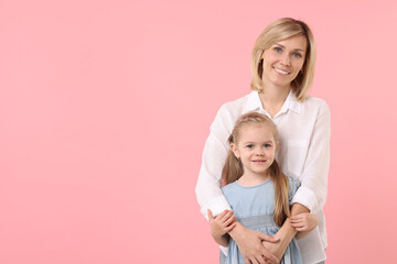 Family portrait of happy mother and daughter on pink background. Space for text