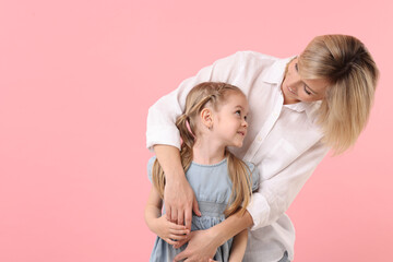 Family portrait of happy mother and daughter on pink background. Space for text