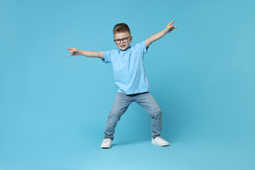 Happy little boy dancing on light blue background